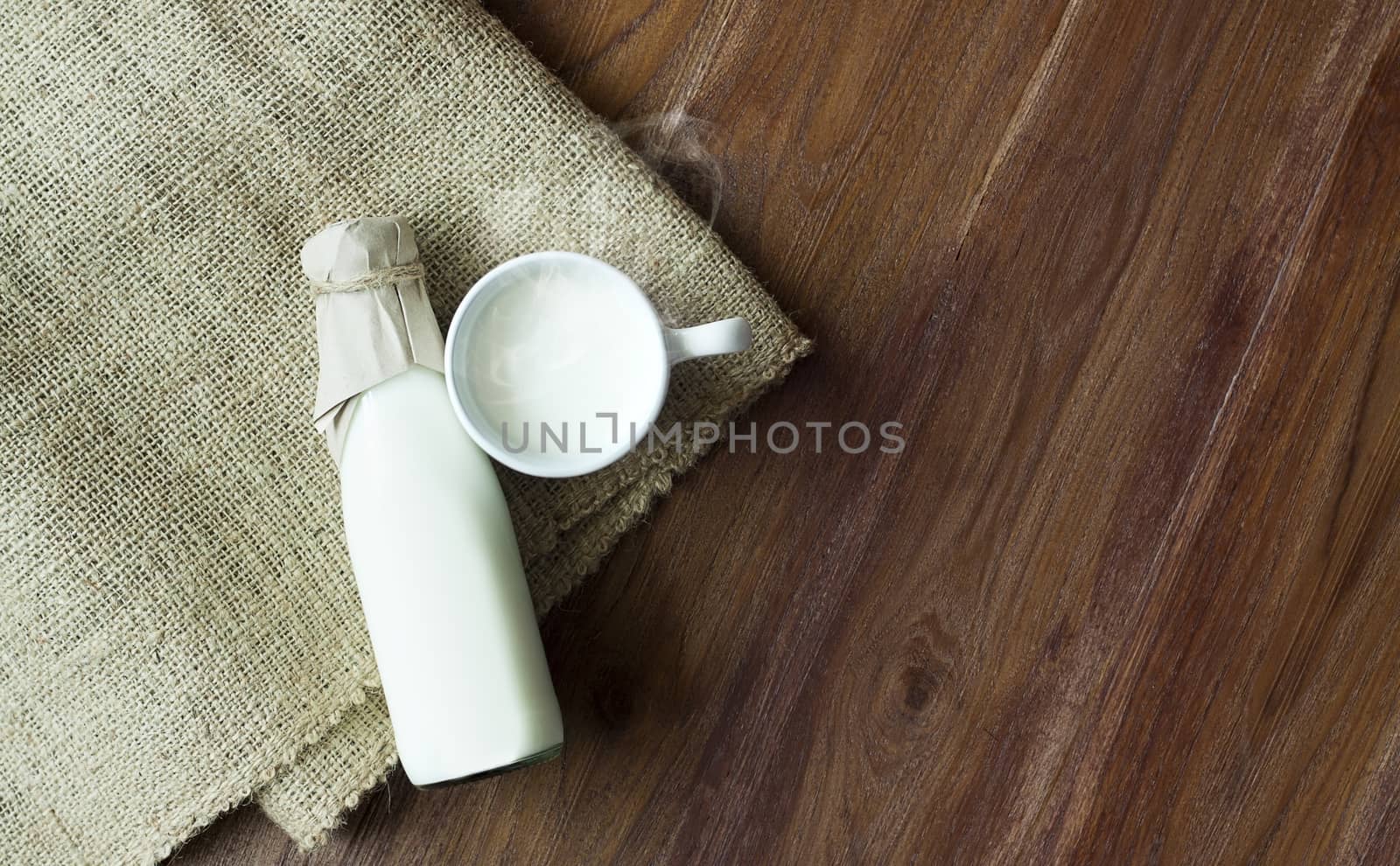 Hot fresh milk in a glass bottle on wooden background by asiandelight
