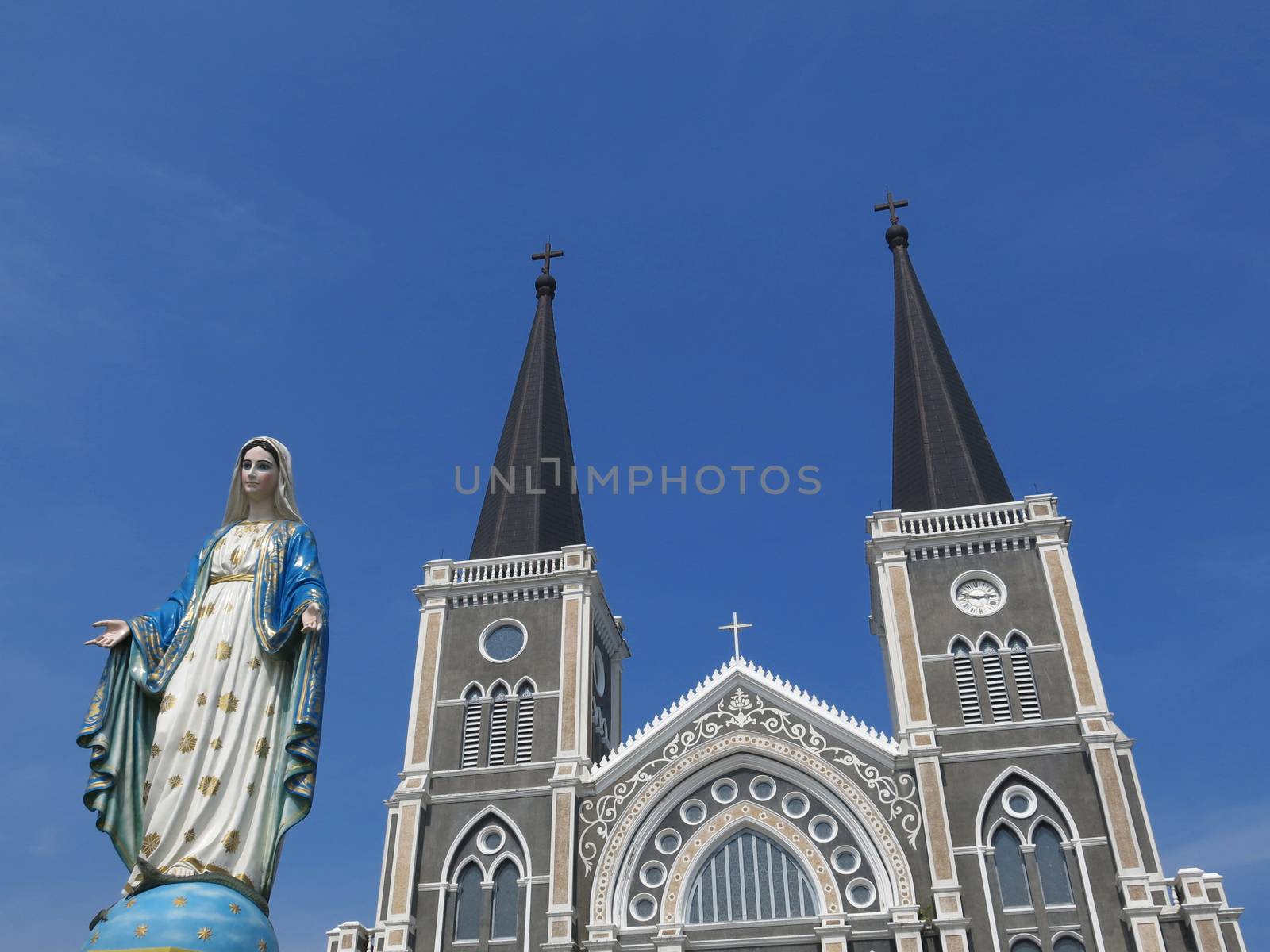 Virgin mary statue in front of church on blue sky background