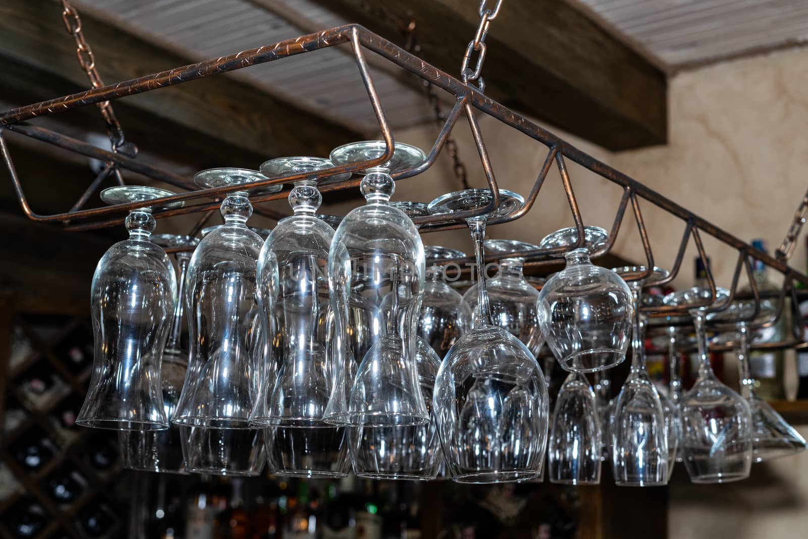 Many glass goblets hang over the bar. Empty glasses