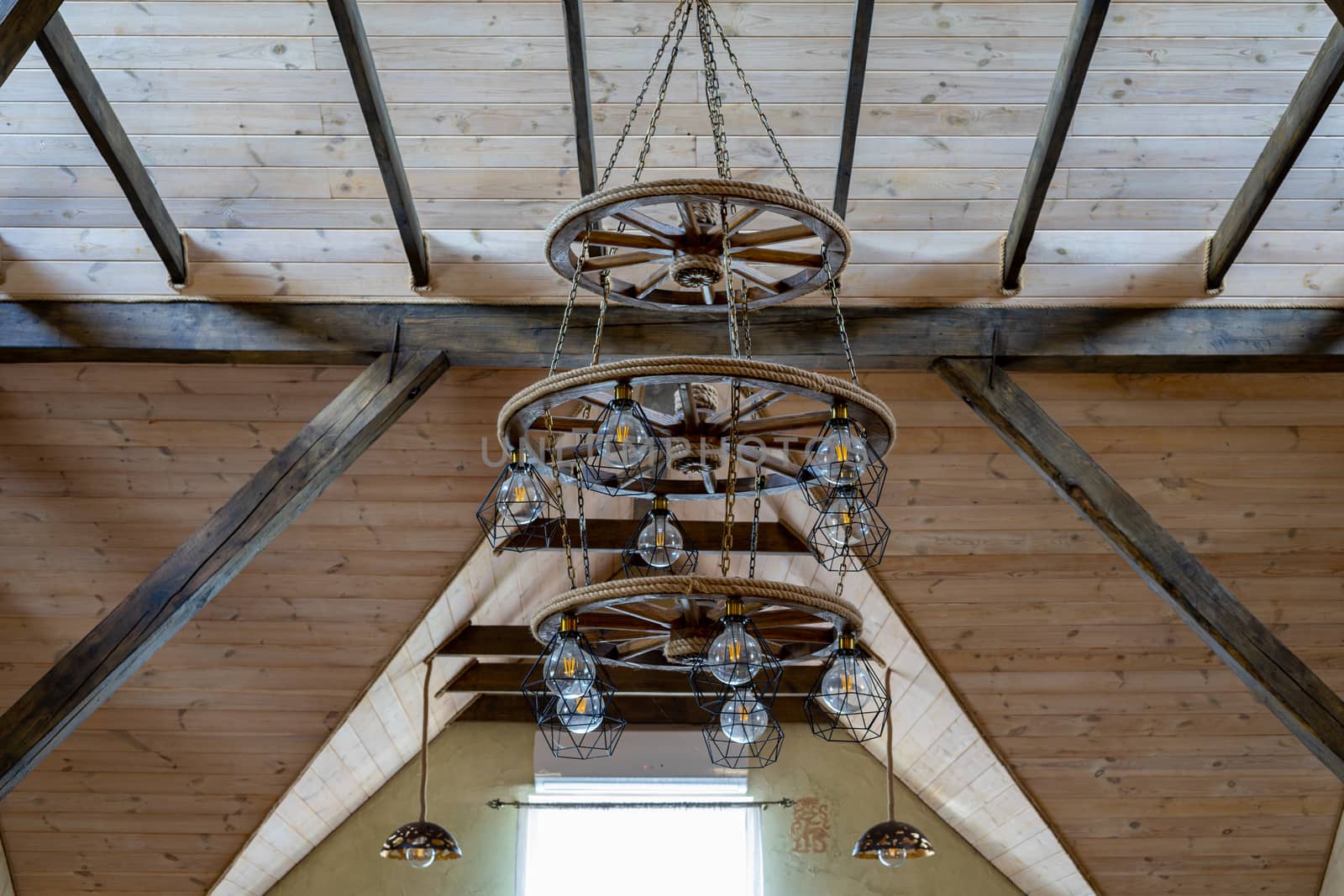 A large chandelier hangs from the ceiling of a wooden house. Wooden interior