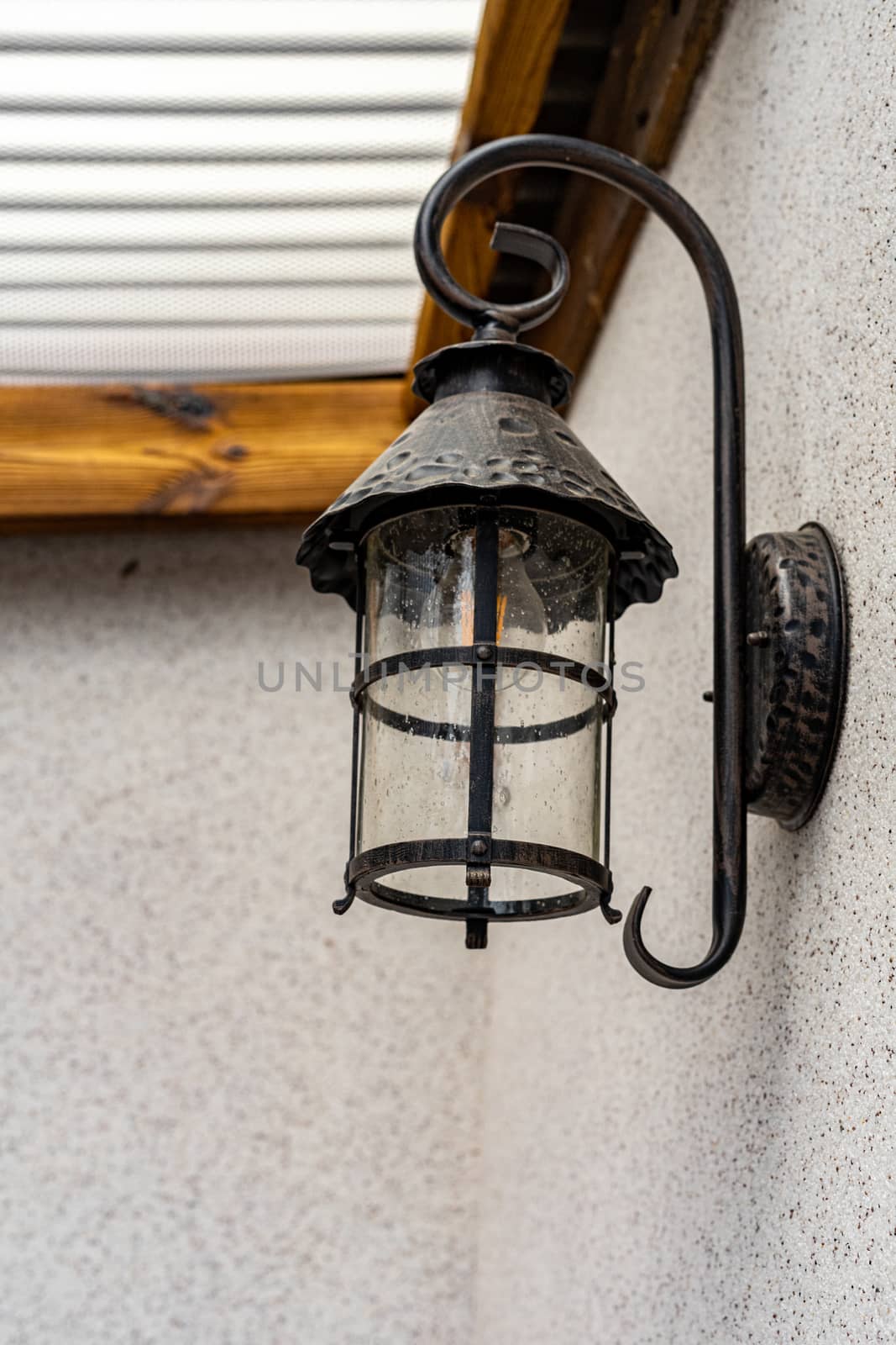 An iron black lamp is attached to the wall. Lamp on the wall close up