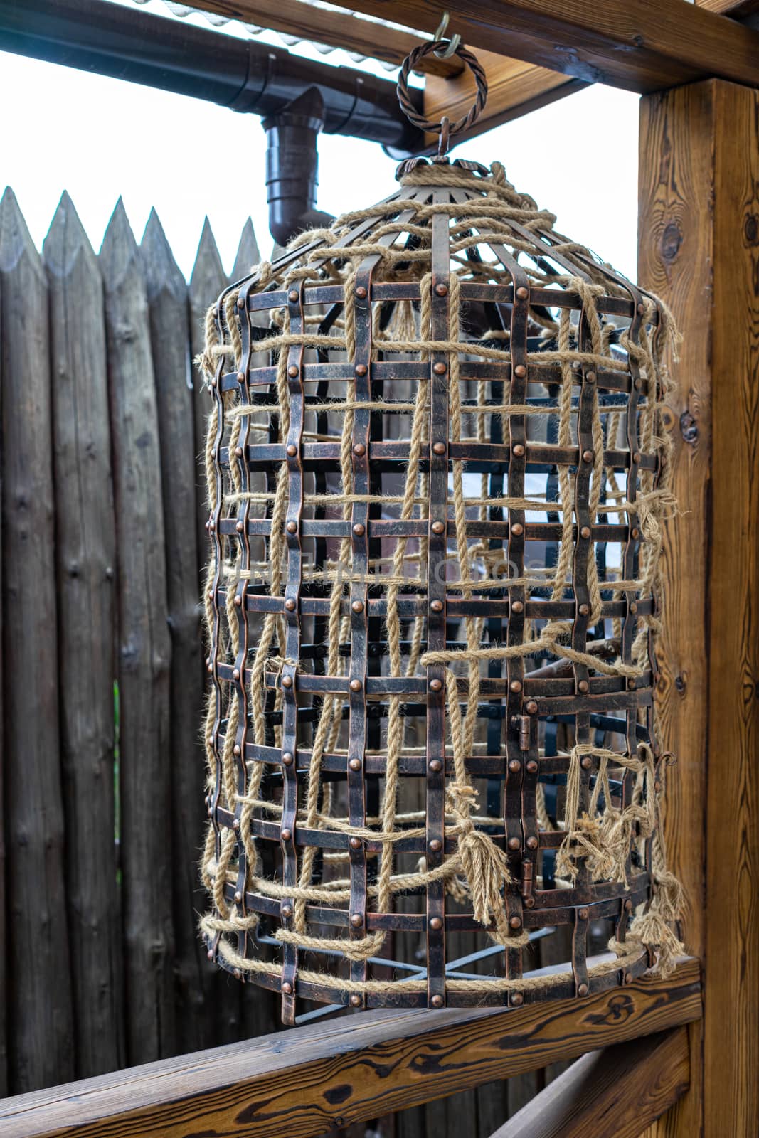 The designer bird cage is made in the old style. The iron cage is decorated with a rope by Serhii_Voroshchuk