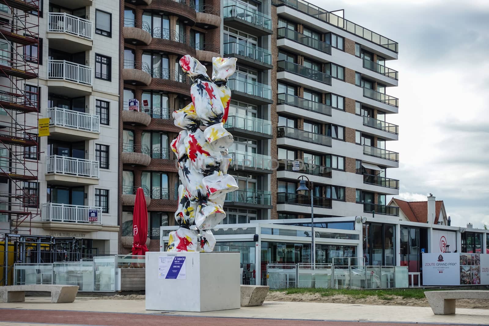 Knokke-Heist, Flanders, Belgium -  June 16, 2019: Knokke-Zoute part of town. Statue of six wrapped candy standing on pedestal with apartment buildings as backdrop. Belgian flag colors.