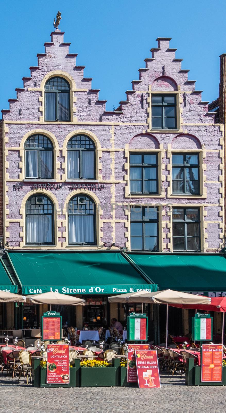 Bruges, Flanders, Belgium -  June 17, 2019: Brick stone facade with step gables, now restaurant La Sirene d’Or with colored awning, on NW side of Markt Square. Menus displayed.