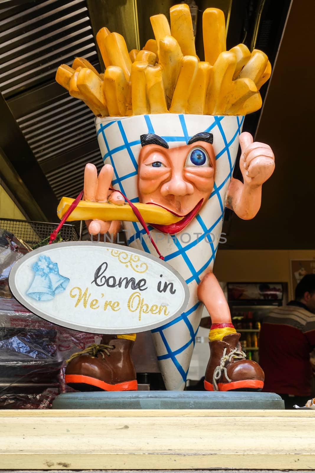 Bruges, Flanders, Belgium -  June 17, 2019: Closeup of colorful French Fries sculpture with human face and arms and legs set in window of fast food restaurant.