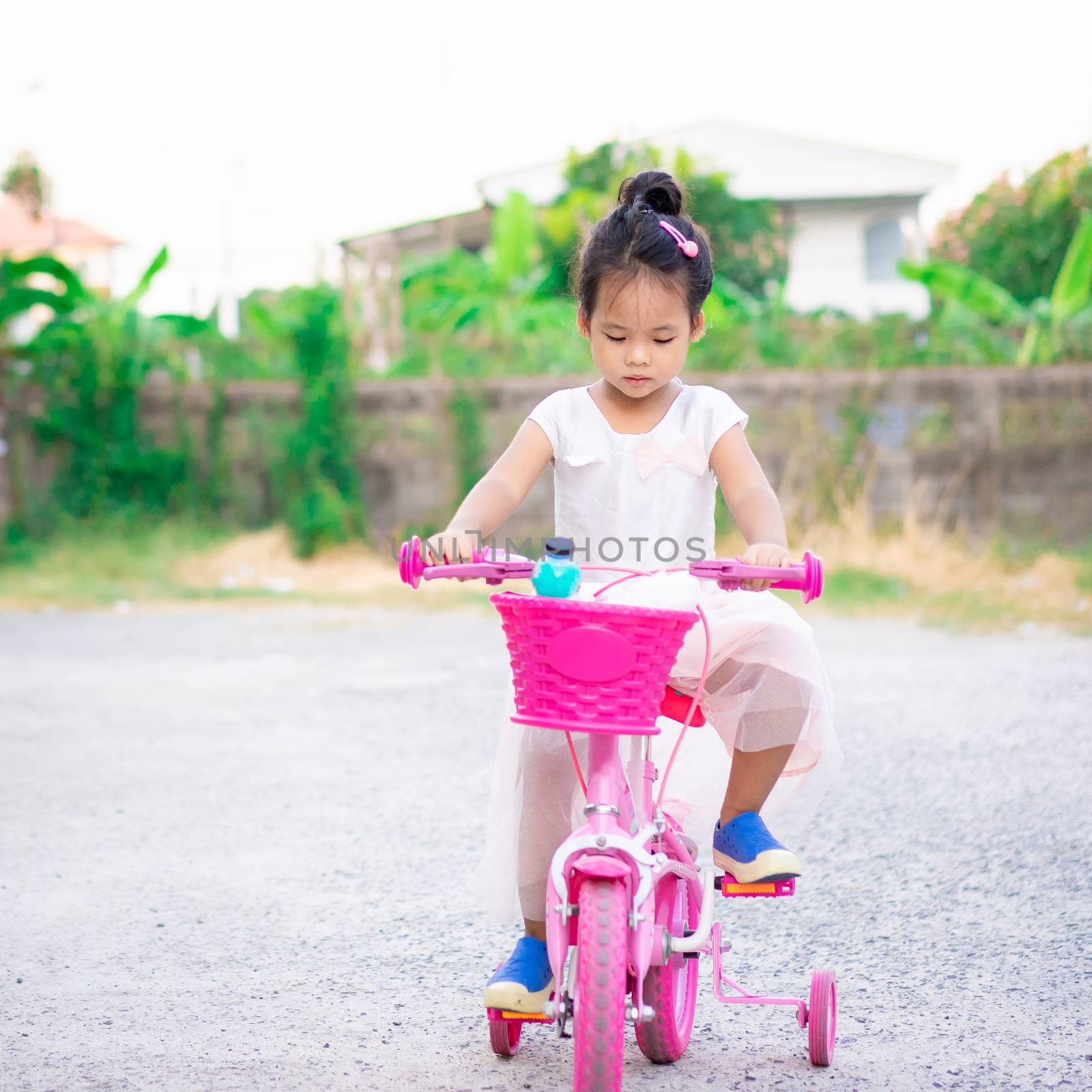 Cute little asian girl riding a bicycle to exercise on the stree by domonite