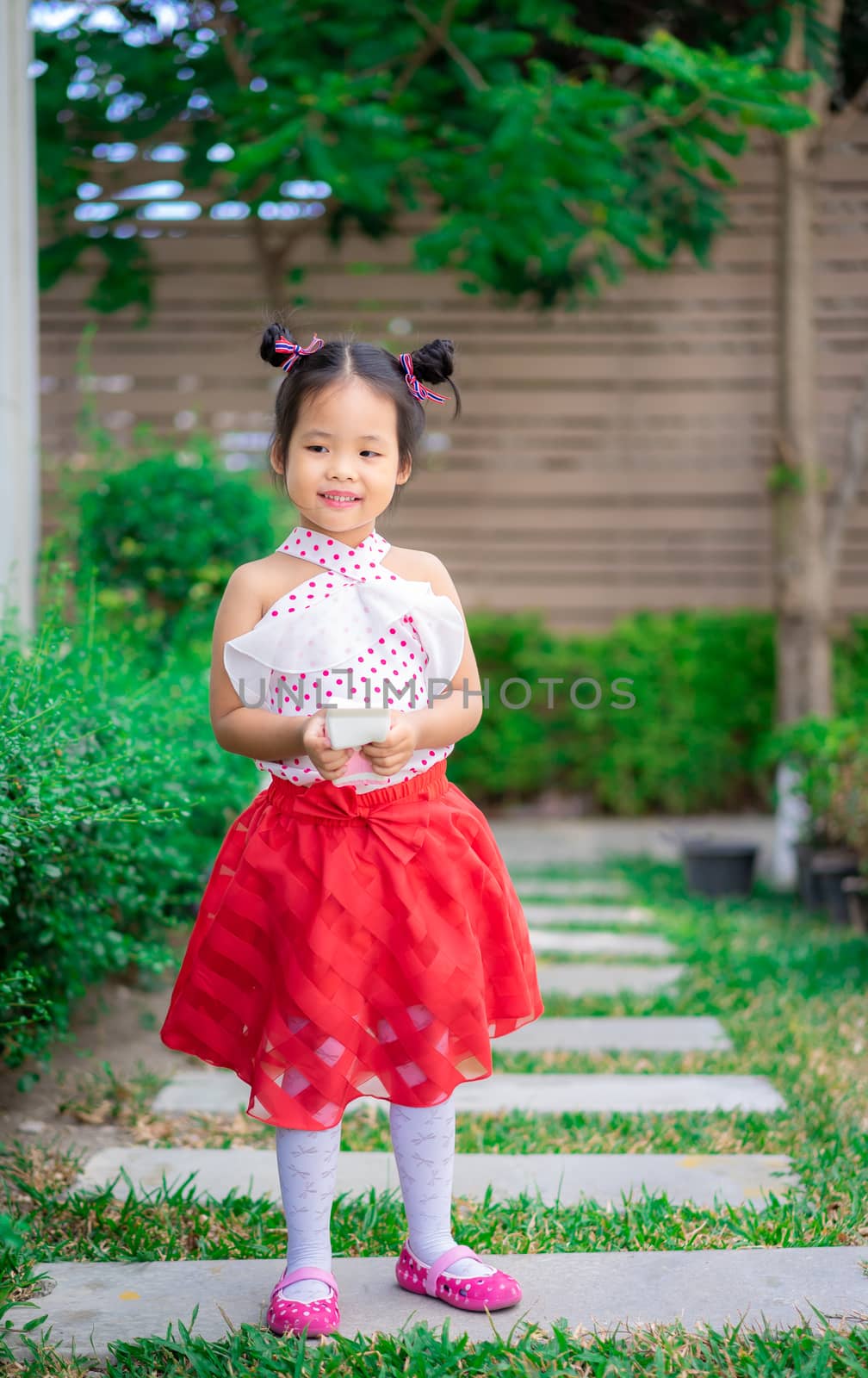 portrait of cute little girl in dress standing in the park