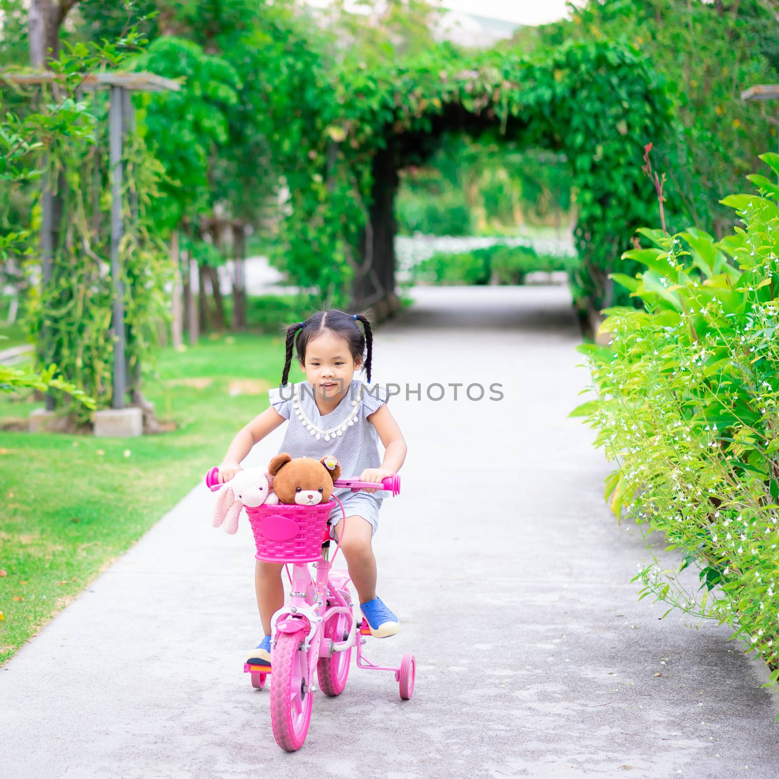 Cute little asian girl riding a bicycle to exercise in park, kid by domonite
