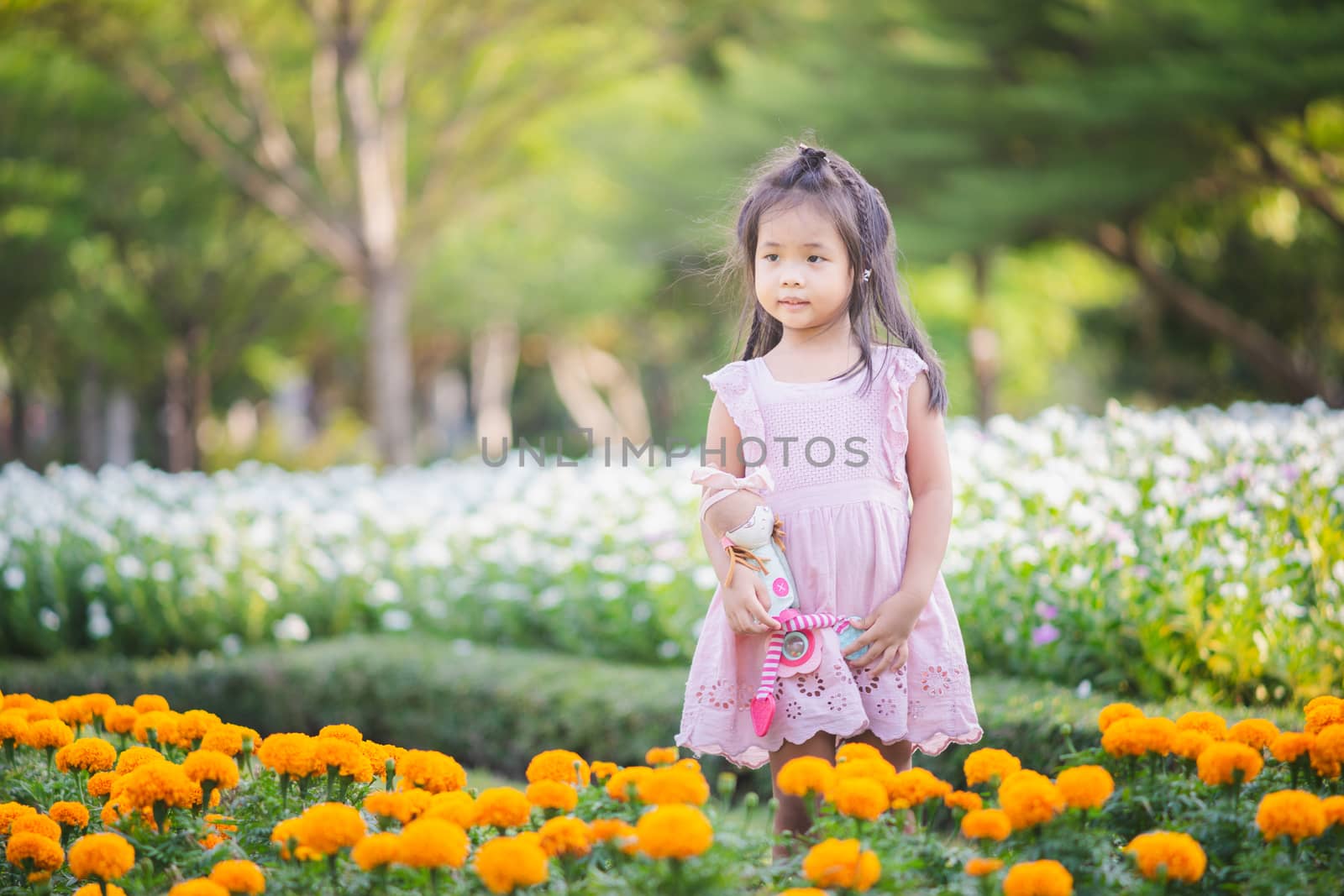 Cute little asian girl with a doll in the garden