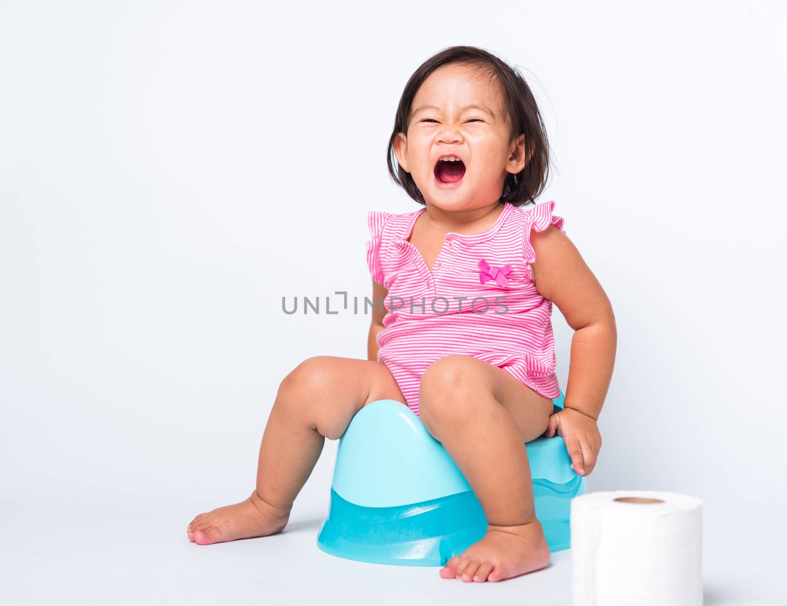 Asian little cute baby child girl education training to sitting on blue chamber pot or potty with toilet paper rolls, studio shot isolated on white background, wc toilet concept