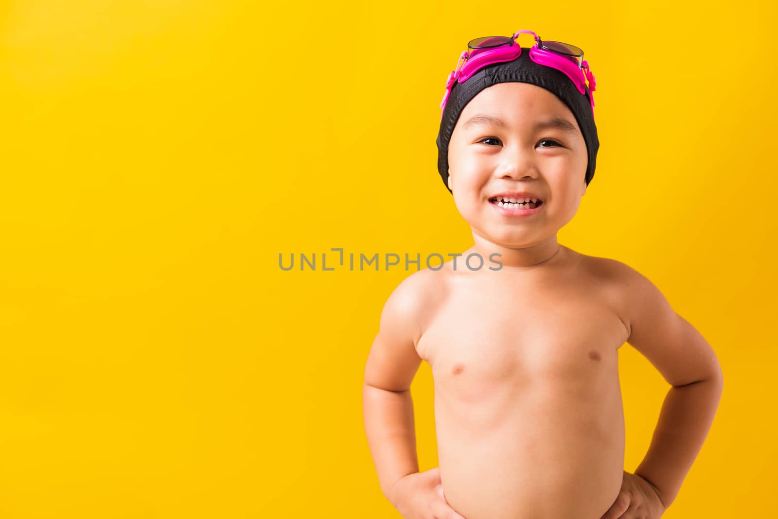 Summer vacation concept, Closeup portrait Asian happy cute little child boy wearing goggles and swimsuit, Kid having fun with in summer vacation looking camera, studio shot isolated yellow background