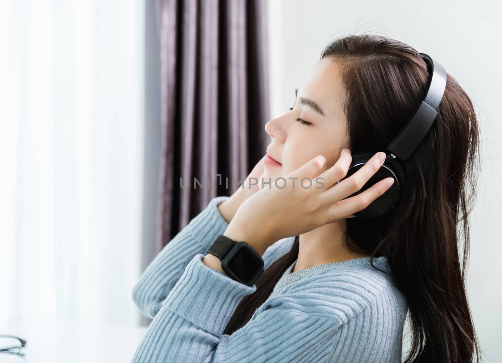 Work from home, Asian young business woman feeling relaxing listening to music with headphones on front laptop computer quarantines disease coronavirus or COVID-19 at home office