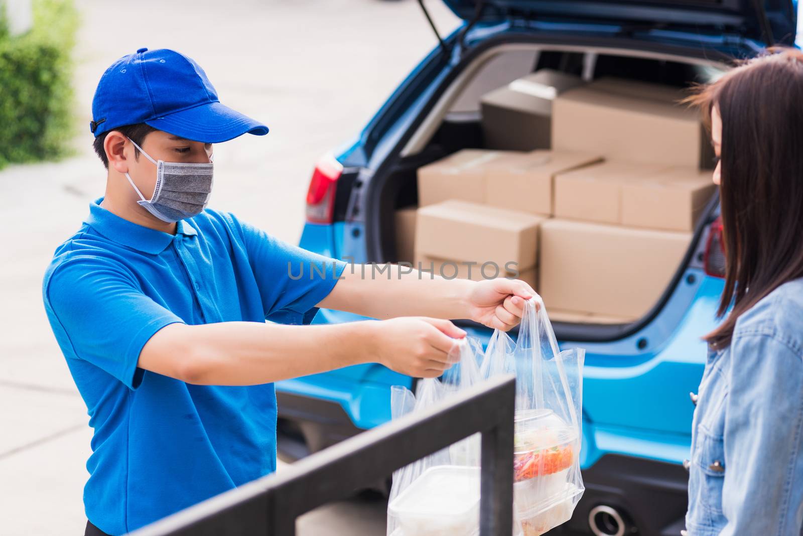 Asian young delivery man wear face mask he making grocery service giving rice food boxes plastic bags to woman customer receiving door at house after pandemic coronavirus, Back to new normal concept