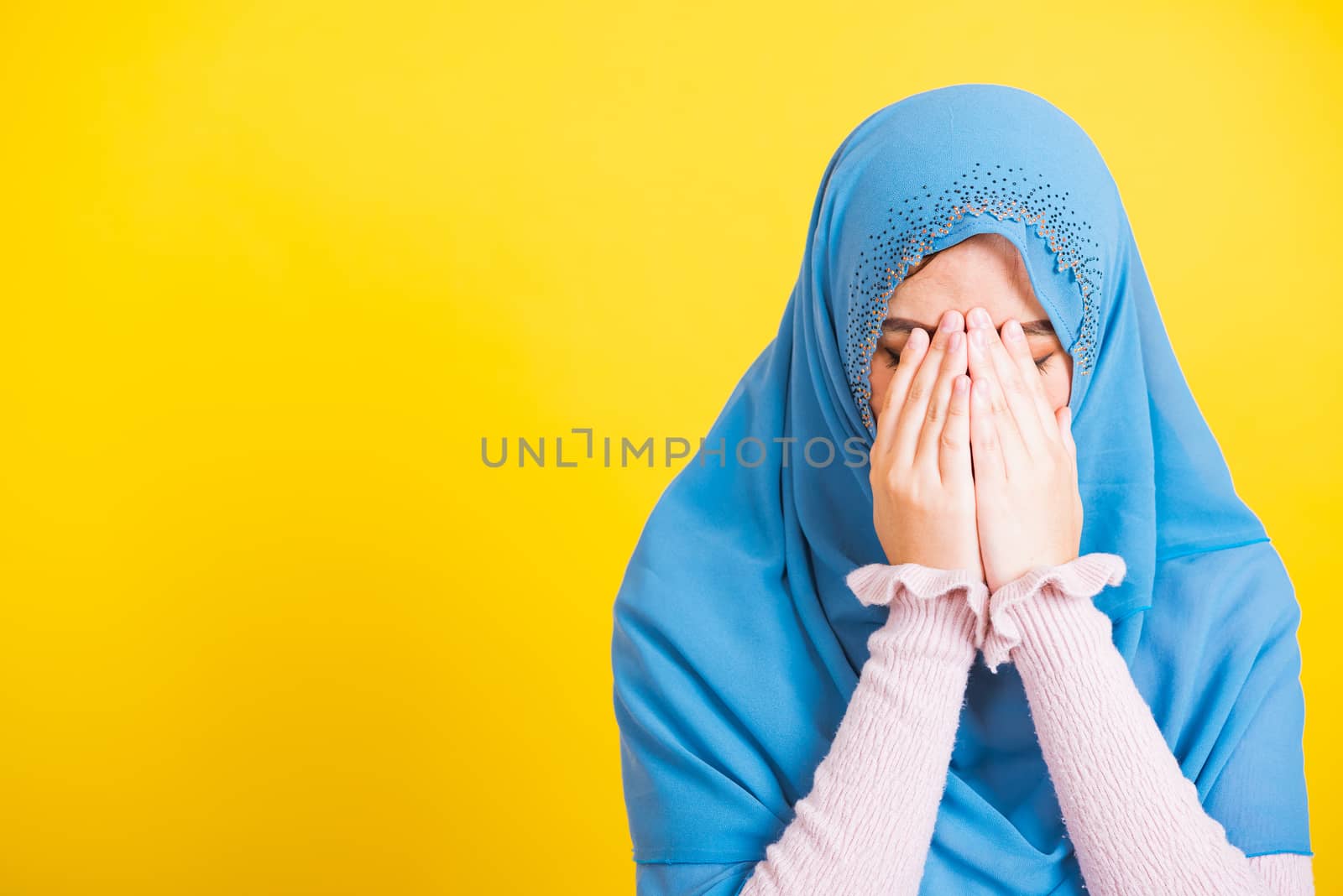 Asian Muslim Arab, Portrait of happy beautiful young woman religious wear veil hijab she sad crying using hand wiping tears in her eyes, studio shot isolated on yellow background with copy space