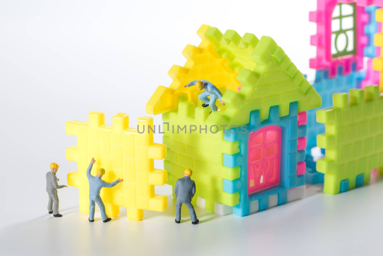 miniature worker people team building the house on white background