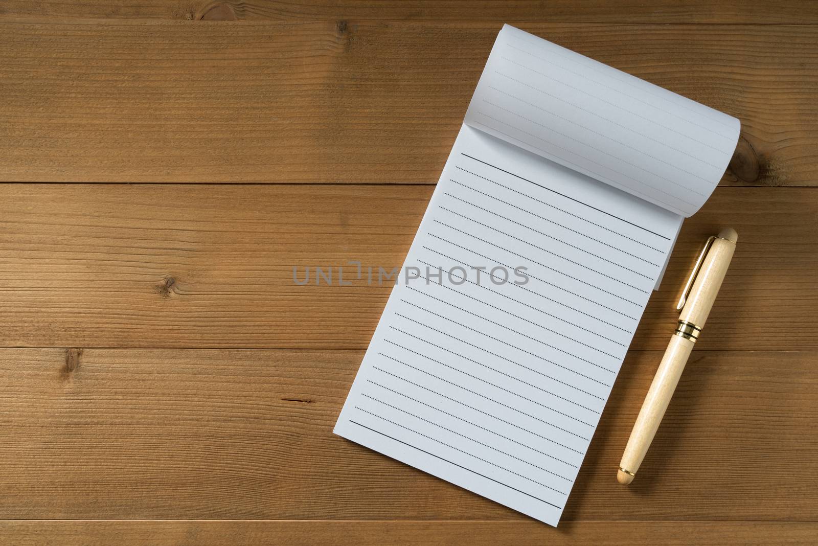 blank notebook with pen on brown wood table