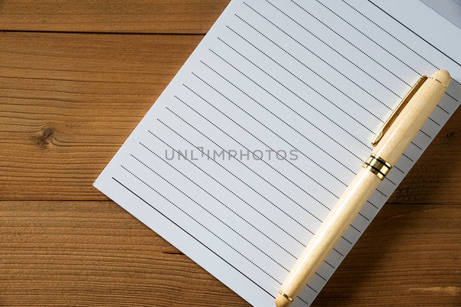 blank notebook with pen on brown wood table