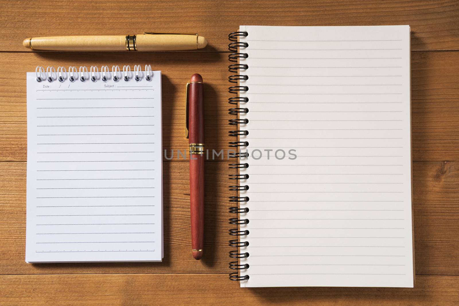 blank notebook with pen on brown wood table