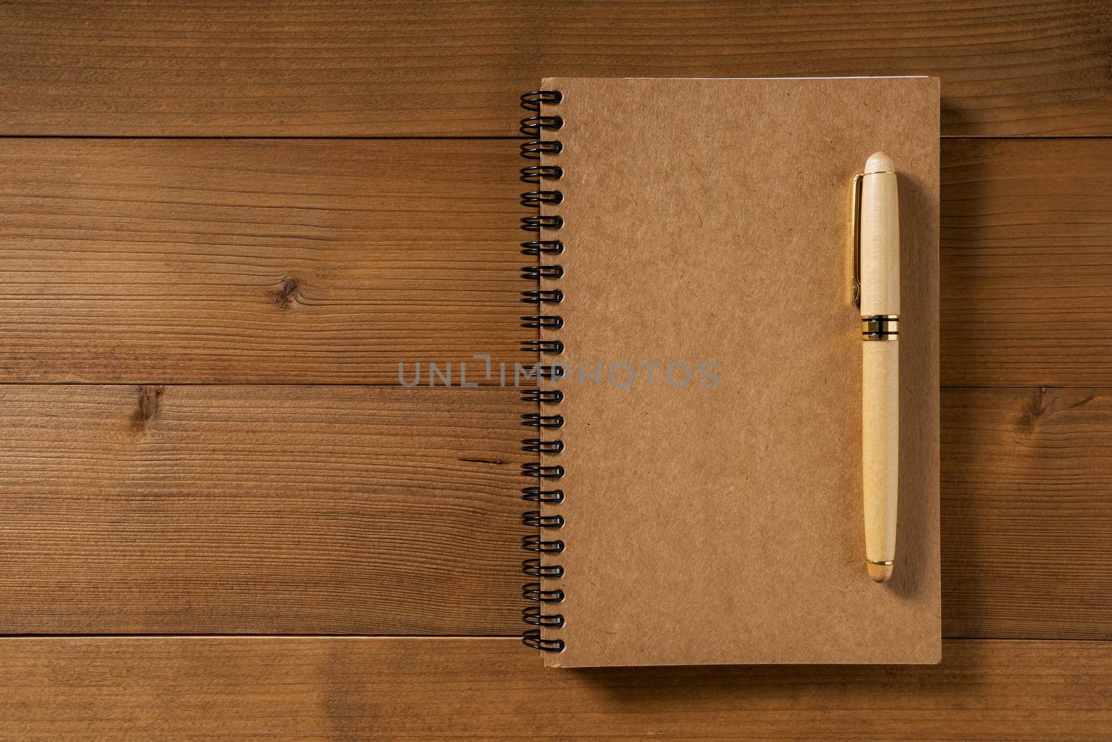 blank notebook with pen on brown wood table