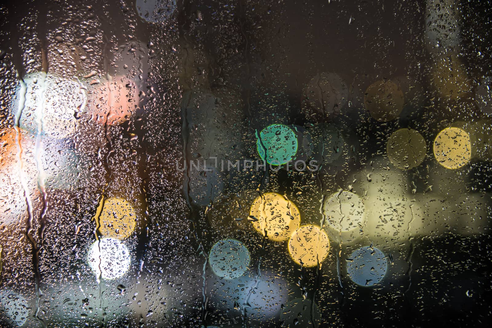 natural water drops on glass window with night city bokeh background
