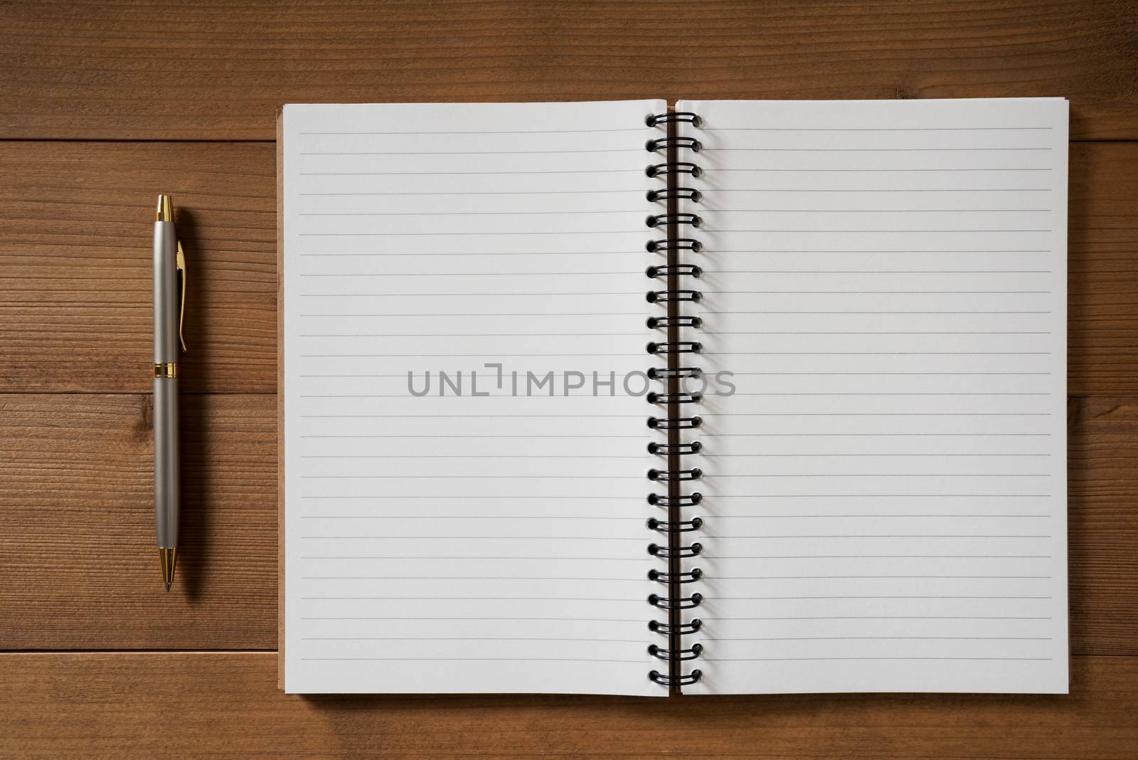 blank notebook with pen on brown wood table