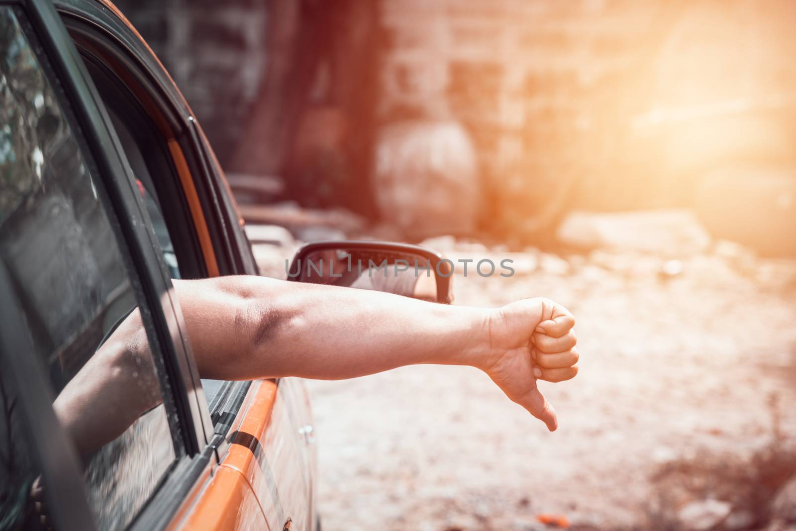 man hand out of the car, shows the symbol thumb down to another car