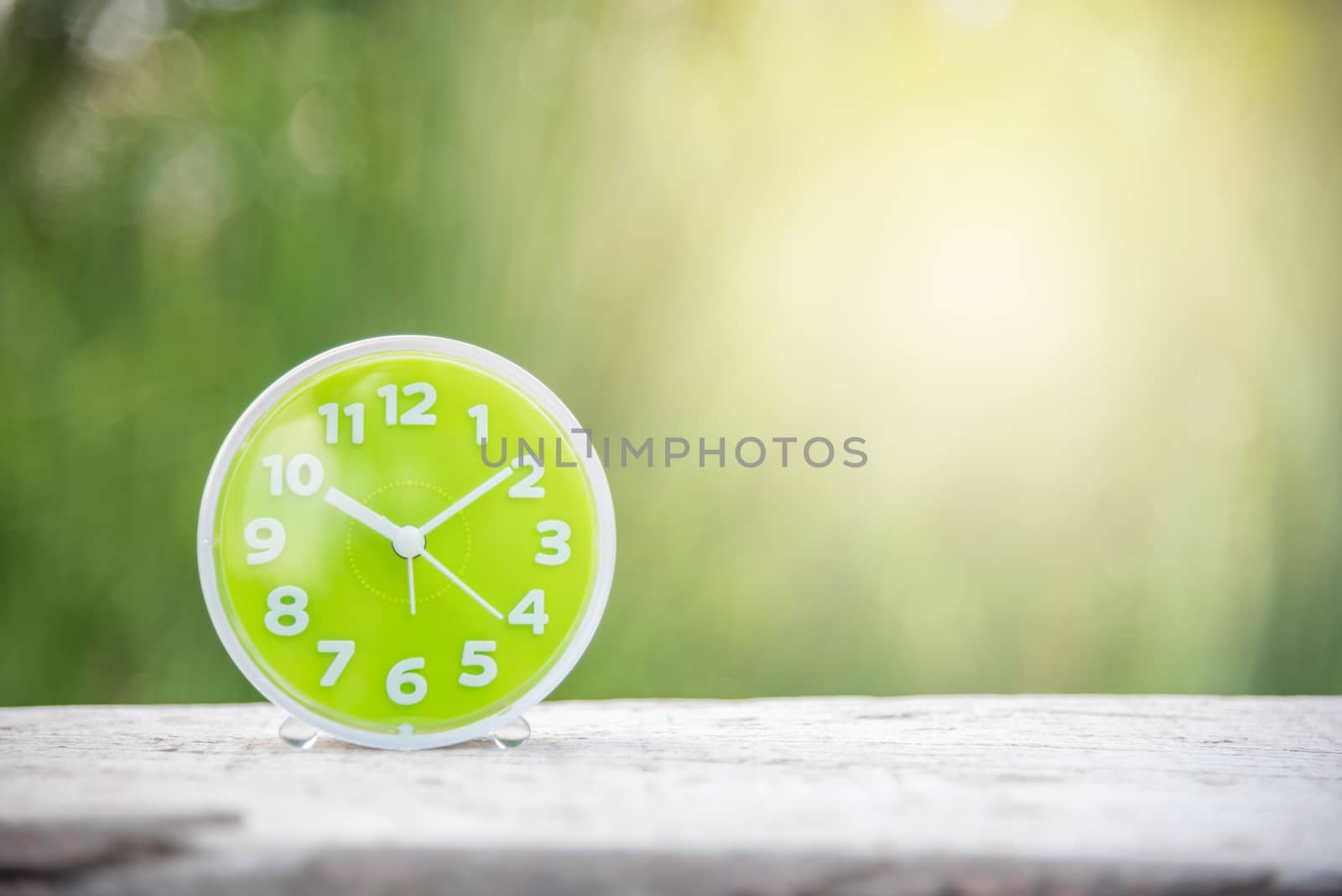 green clock on white wood and green natural background