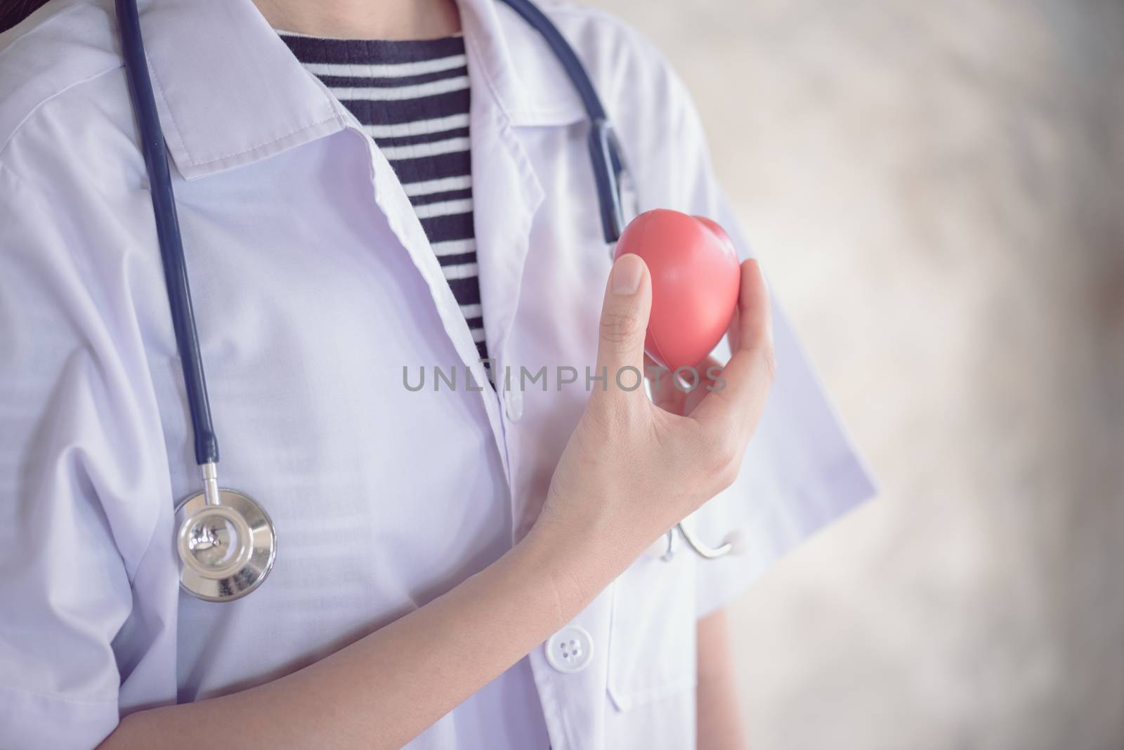 profressional woman doctor with green stethoscope and red heart in her hand