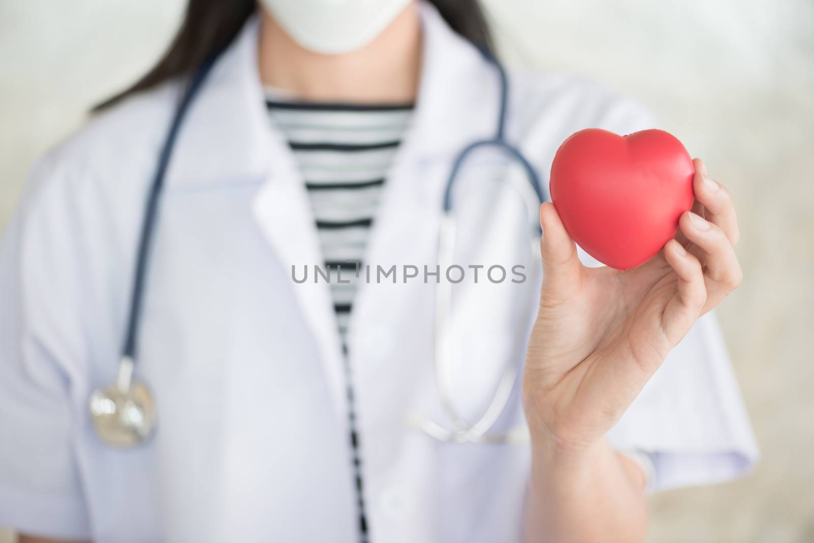 profressional woman doctor with green stethoscope and red heart in her hand