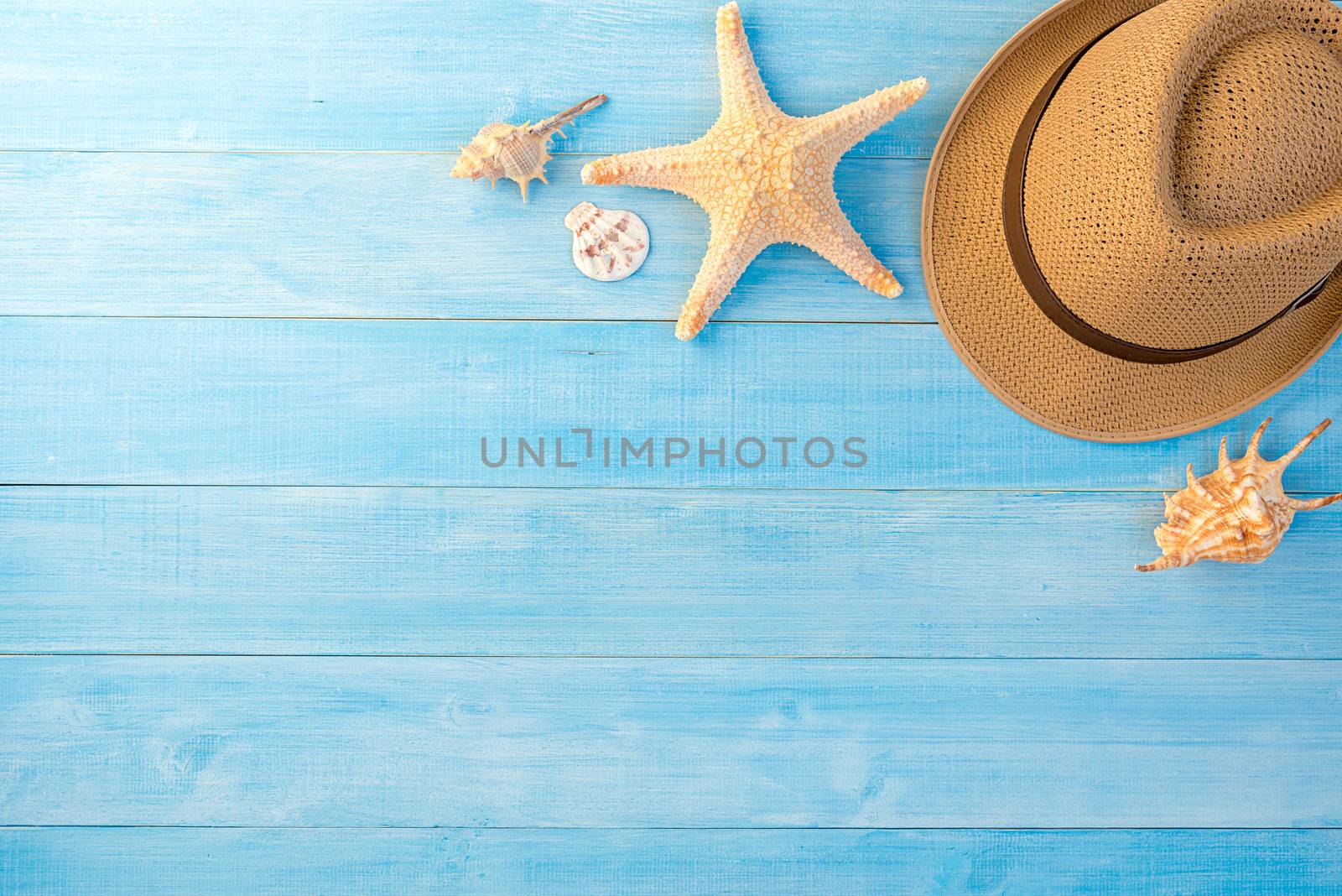 top view of hat and sea shell on light blue wood plank floor for summer vacation time background