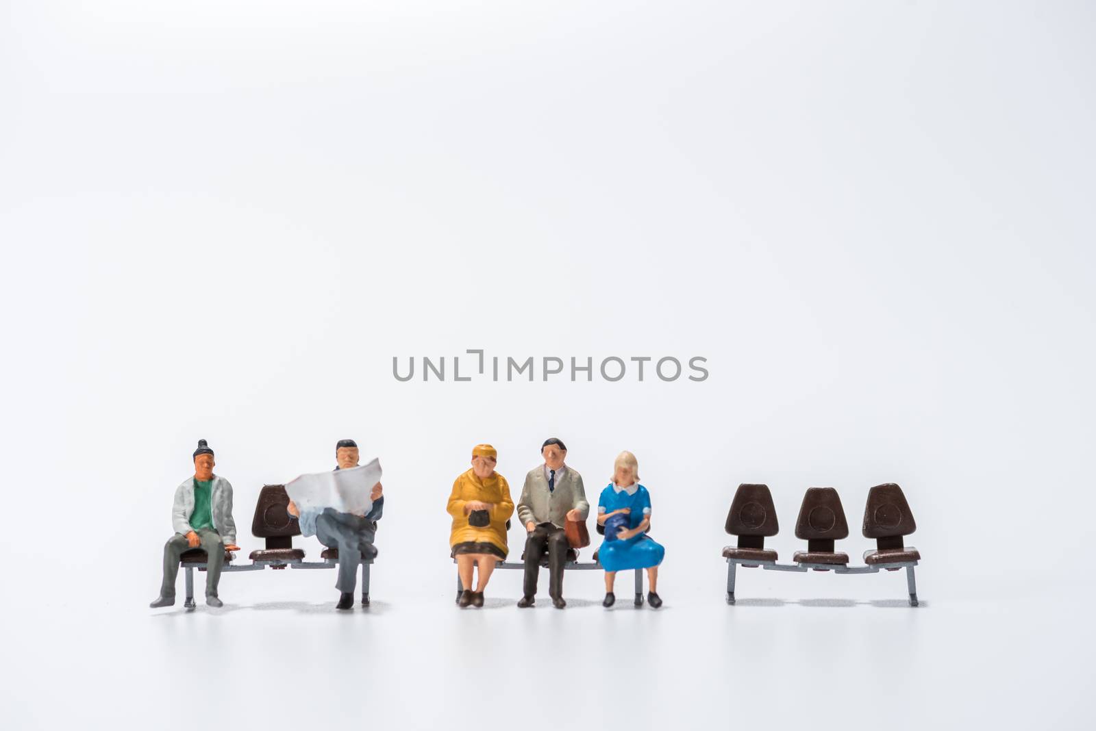 row of miniature people figure sitting on bench white background