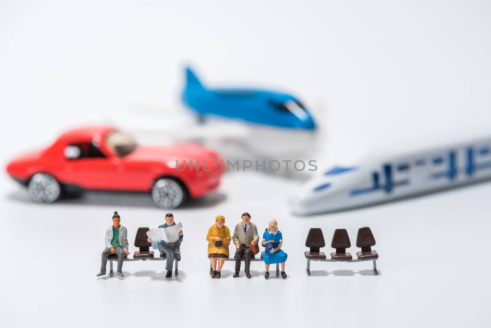 row of miniature people figure sitting on bench with air plane,car,hispeed train model figure background