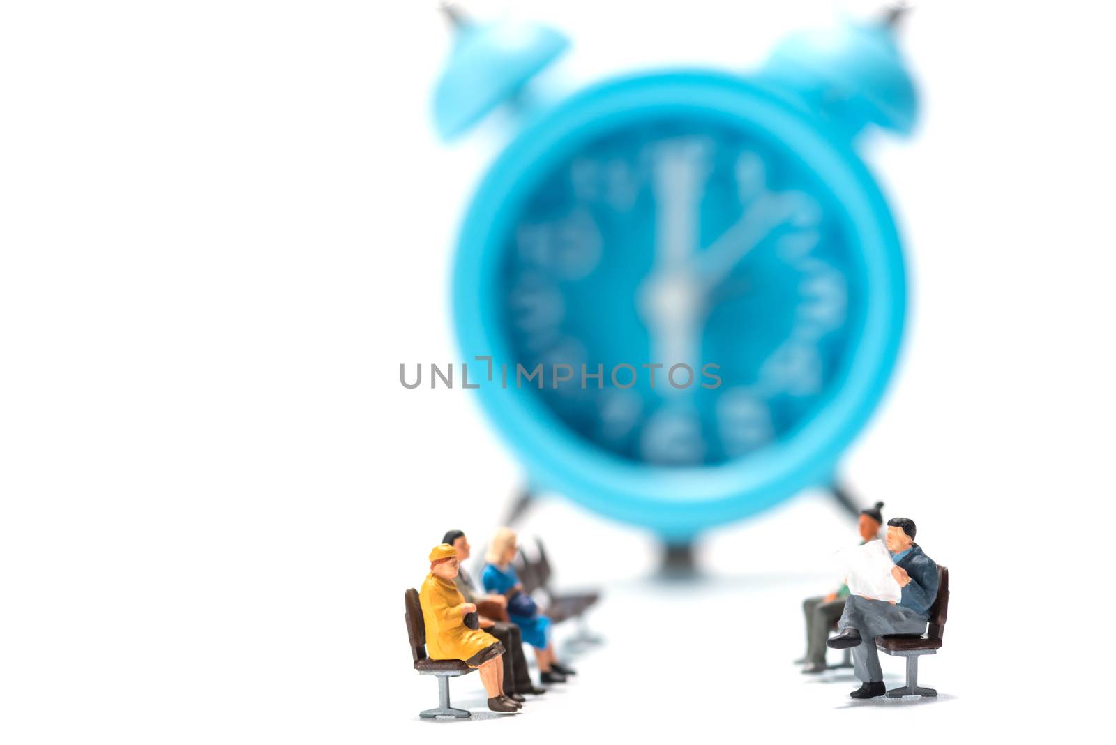 row of miniature people figure sitting on bench with alarm clock background