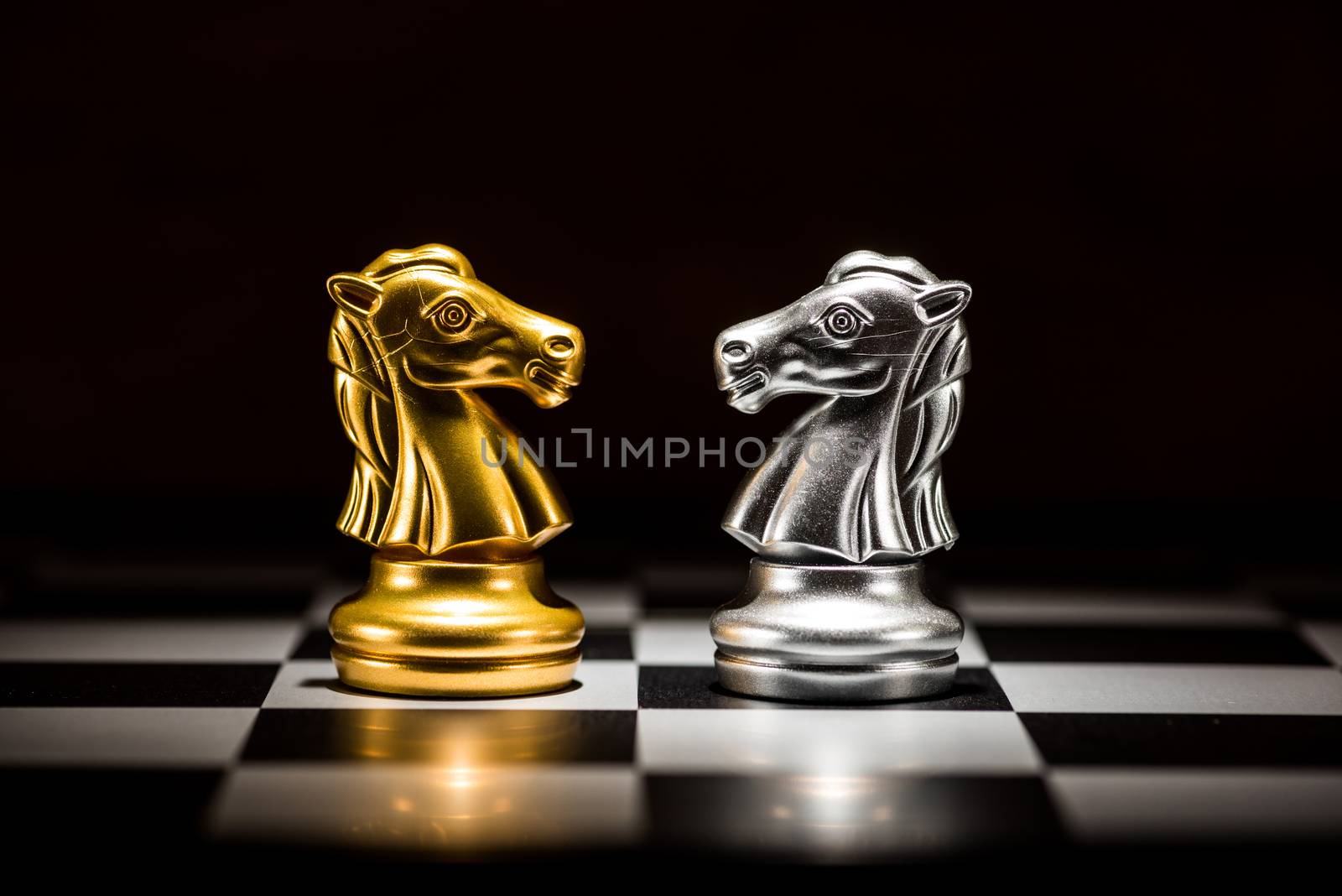 gold knight chess facing silver knight chess on chess board , business strategy concept
