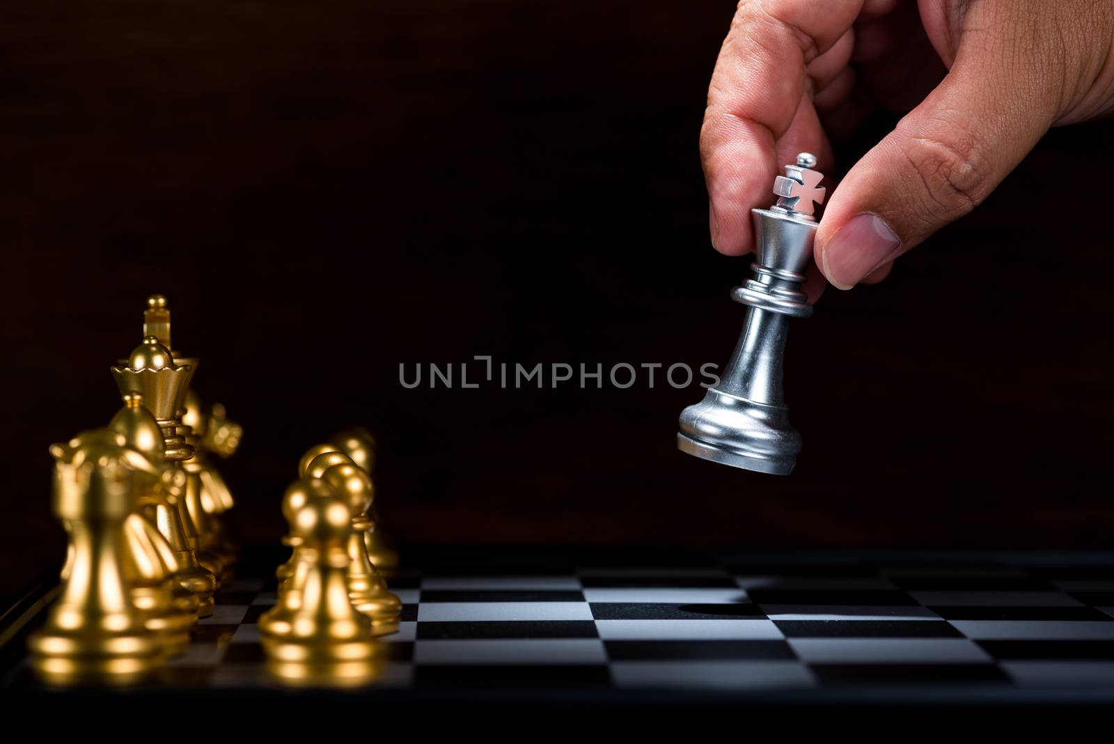 business man moving silver king chess figure to the board , fight with gold chess team , business leader concept