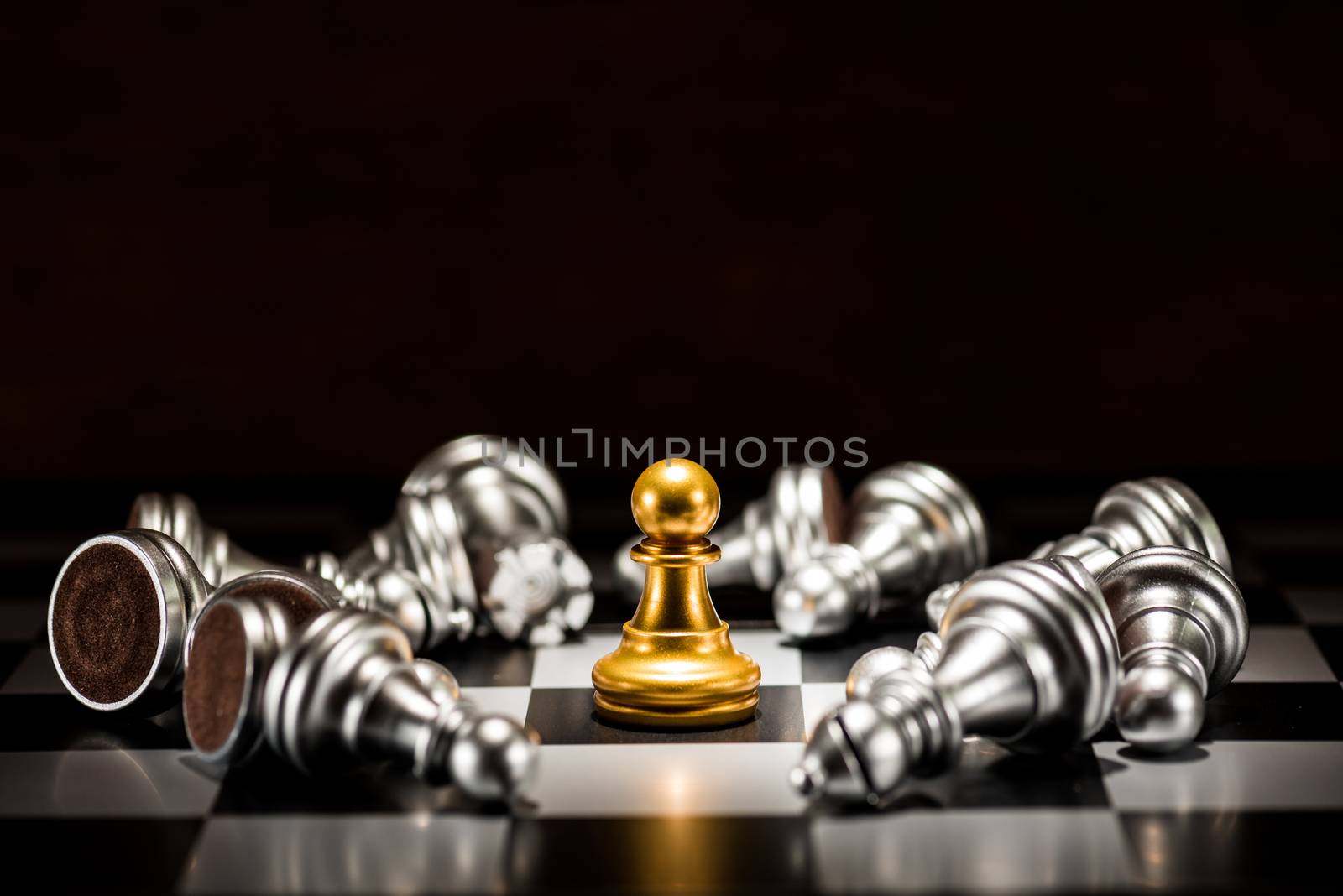 single gold pawn chess surrounded by a number of fallen silver chess pieces , business strategy concept