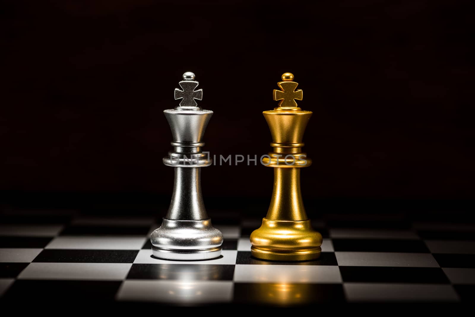 gold king chess facing silver king chess on chess board , business strategy concept