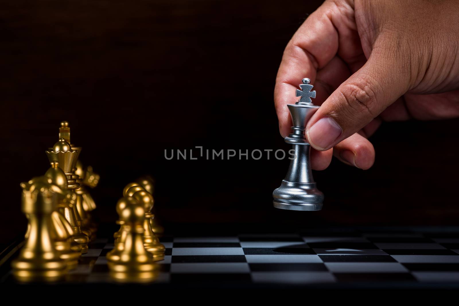 business man moving silver king chess figure to the board , fight with gold chess team , business leader concept