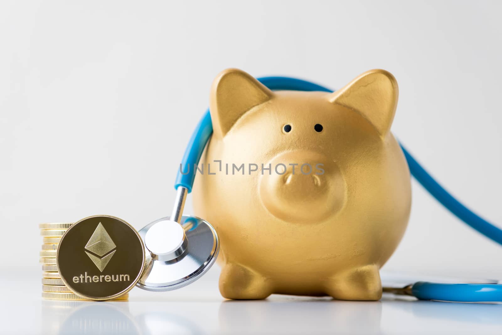 piggy bank with stethoscope and cryptocurrency  ethereum coins on white background.