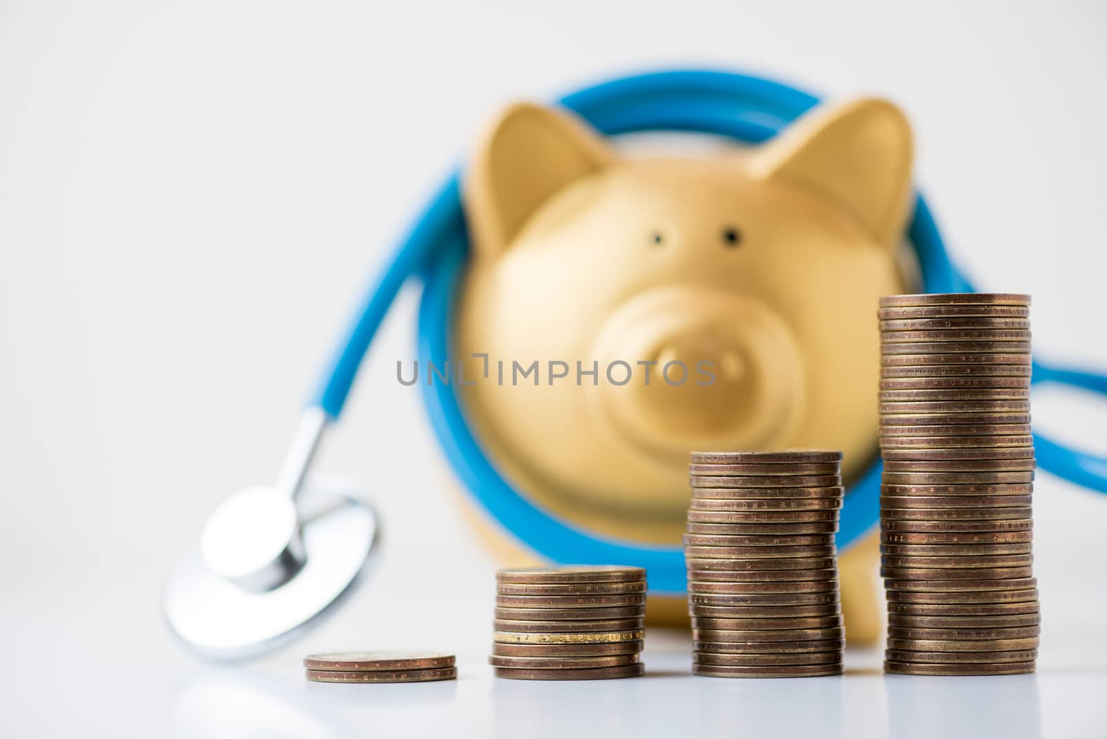 piggy bank with stethoscope and coins stack on white background.