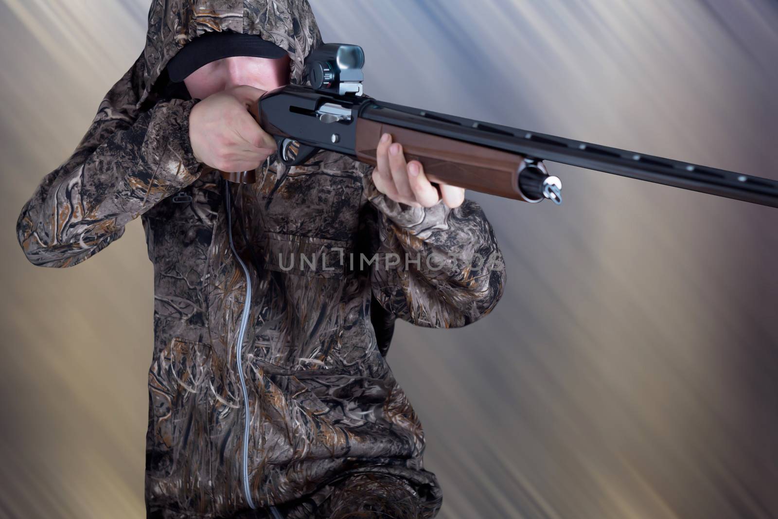 Hunter in camouflage clothing with a gun on abstract background. The man with the shotgun. Young guy in a camo suit with a gun. Soldier, trooper on abstract background.