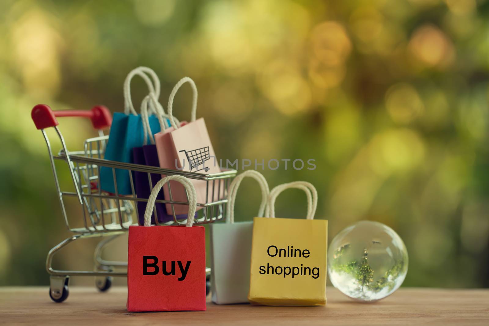 Shopping Online and e-commerce concept: Paper bag in a shopping cart and crystal globe. by setila