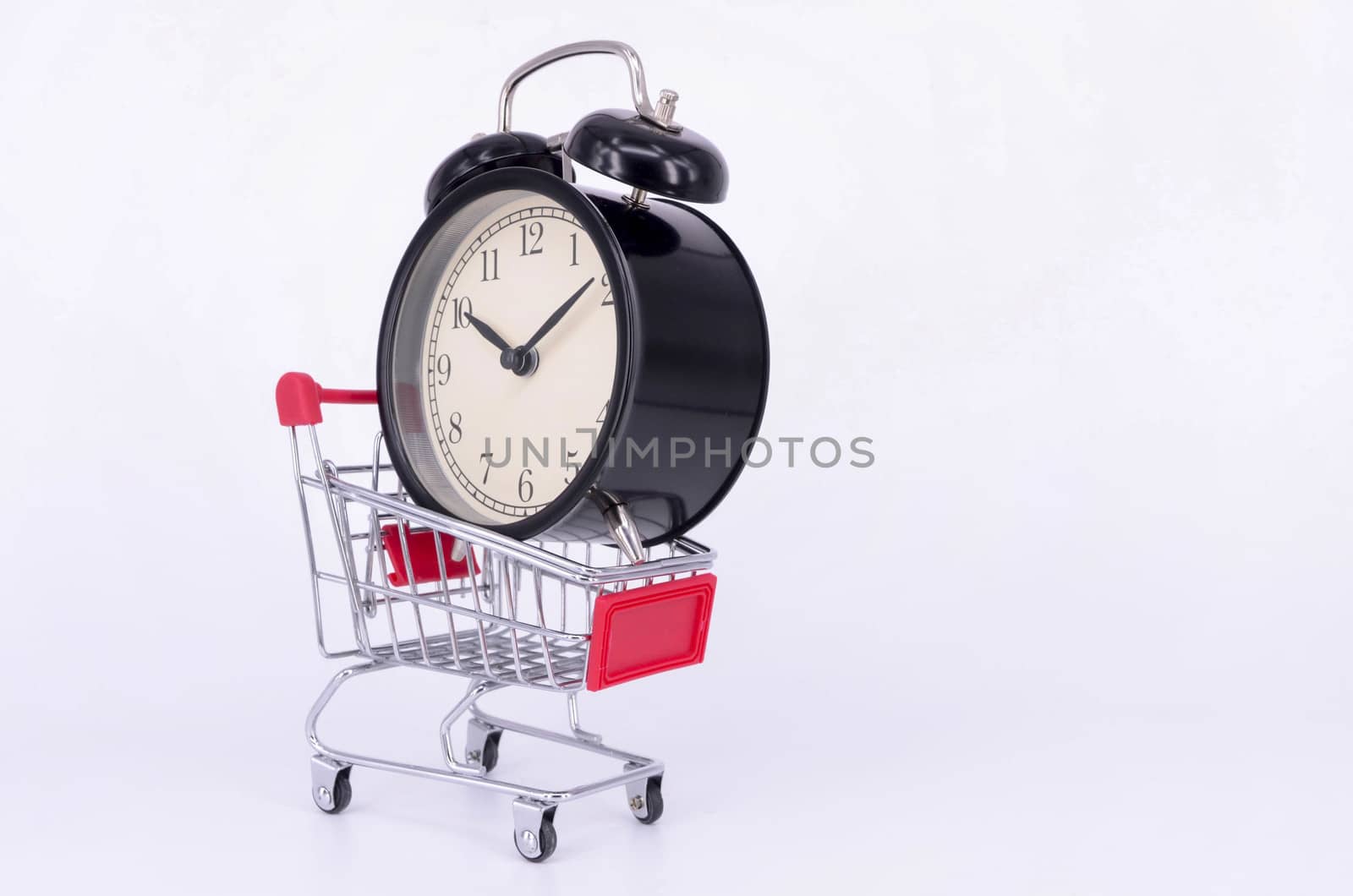 Shopping cart and classic alarm clock on white background. Sale time buy mall market shop consumer concept. Selective focus.