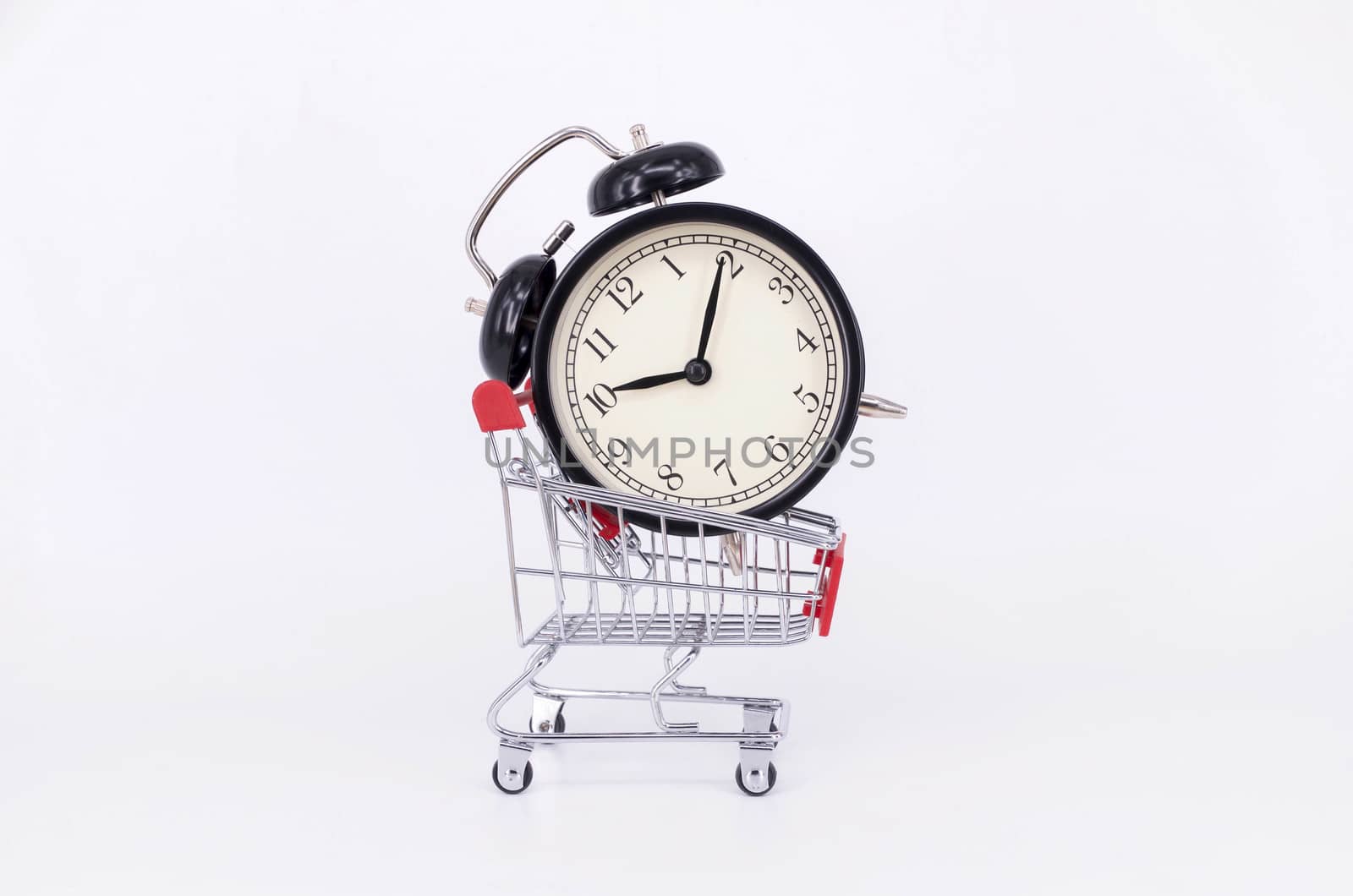 Shopping cart and classic alarm clock on white background. Sale time buy mall market shop consumer concept. Selective focus.