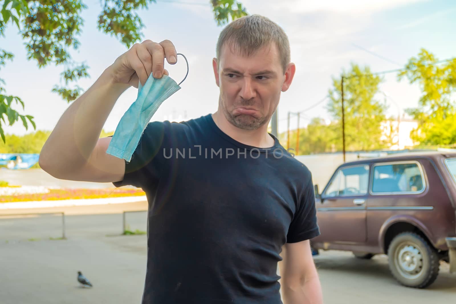 antibacterial medical mask in the hand of a person who expresses an emotion of dislike to wear it