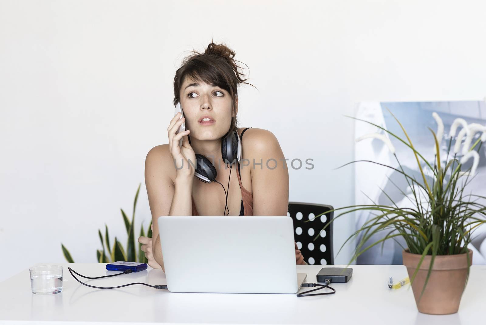 Young freelance woman working on the phone and laptop by raferto1973