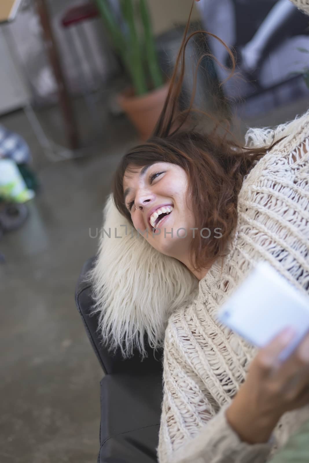 Image of smiling nice woman using cellphone while lying on sofa by raferto1973