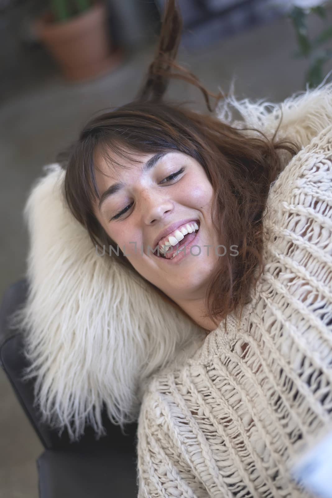 Beautiful joyful girl laying on brown sofa and laughing