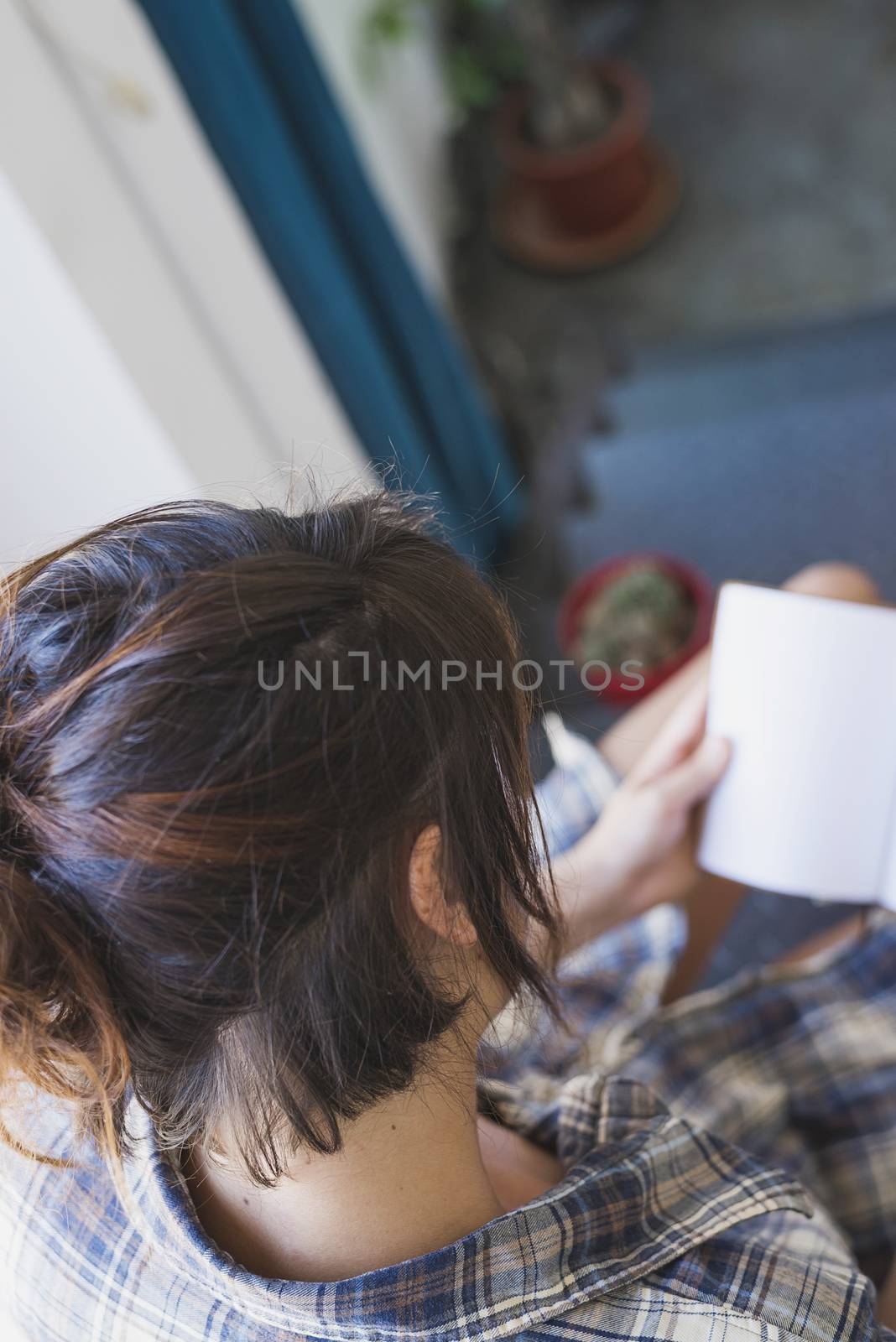 Top view of a young woman sitting on home staircase while reading a book by raferto1973