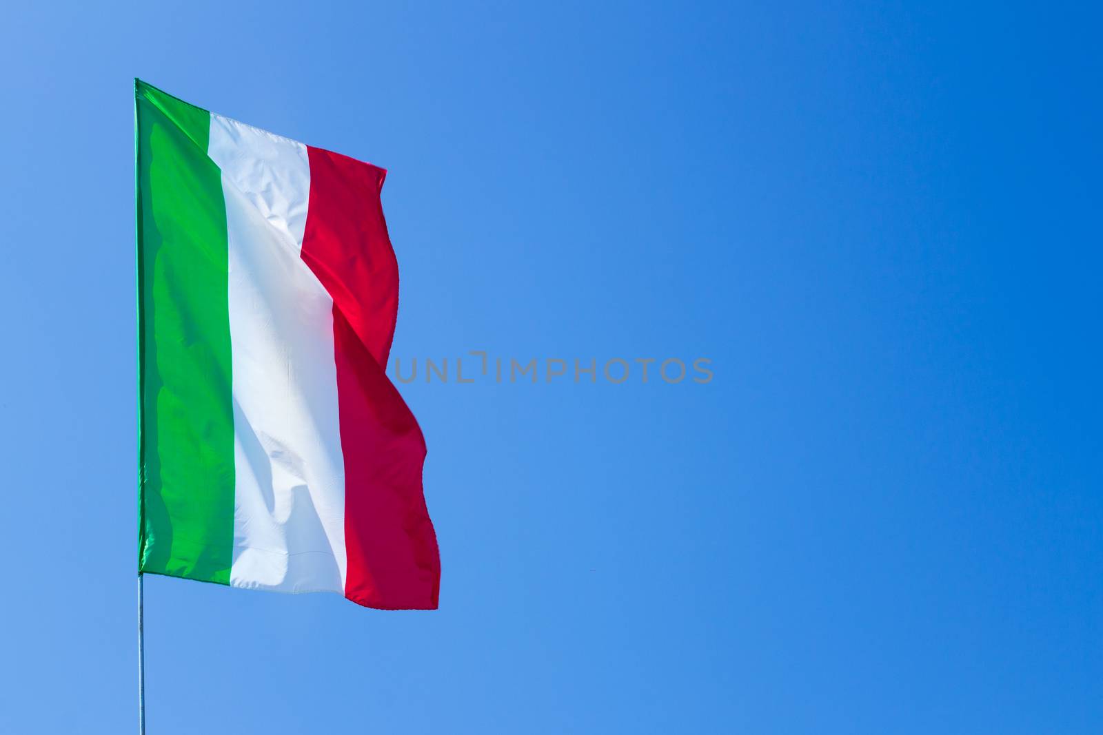 Waving Italian flag against blue sky